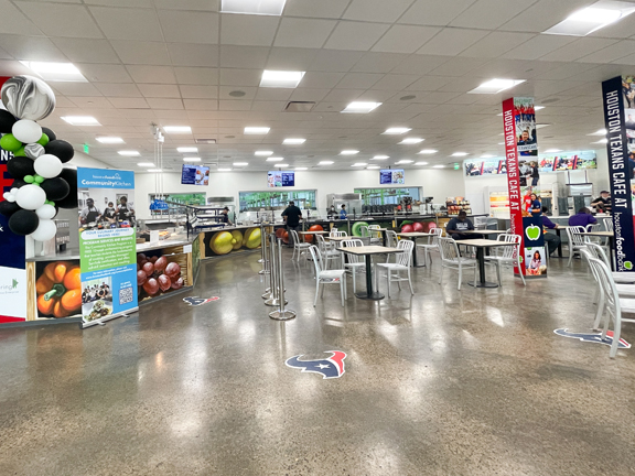 Tables and cafeteria-style rails adorned with painted with realistic versions of fresh produce in the newly renovated Texans Cafe