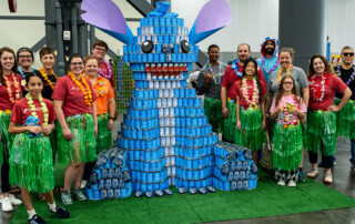 Canstruction 2025, a team poses with their Stitch sculpture.