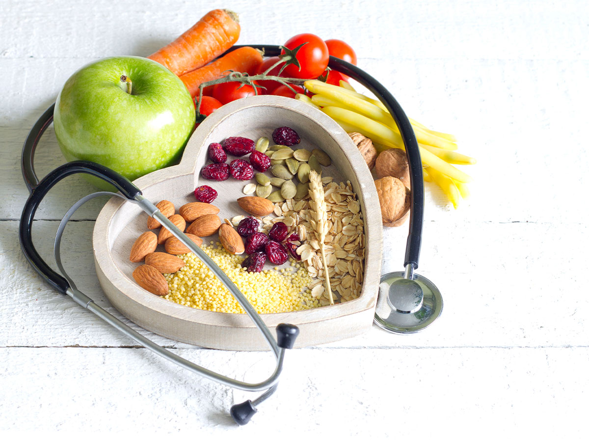 photo of a bowl full of grains surrounded by fruits and vegetables, as well as a stethoscope.