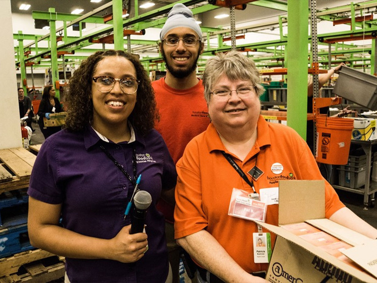 Two female volunteers and one male volunteer in the carousel area of Houston Food Bank.