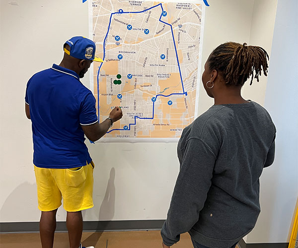 A man and a woman interact with the map of Southeast Texas