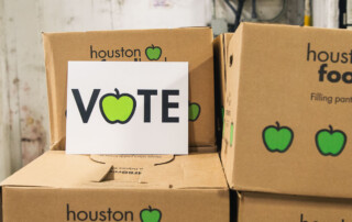 A sign saying Vote on top of Houston Food Bank emergency boxes.