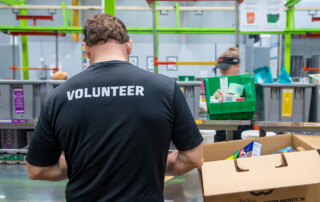 Photo of a man in the Carousel room of Houston Food Bank with Volunteer on the back of his shirt.