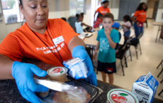 A volunteer prepares summer meals for waiting kids.