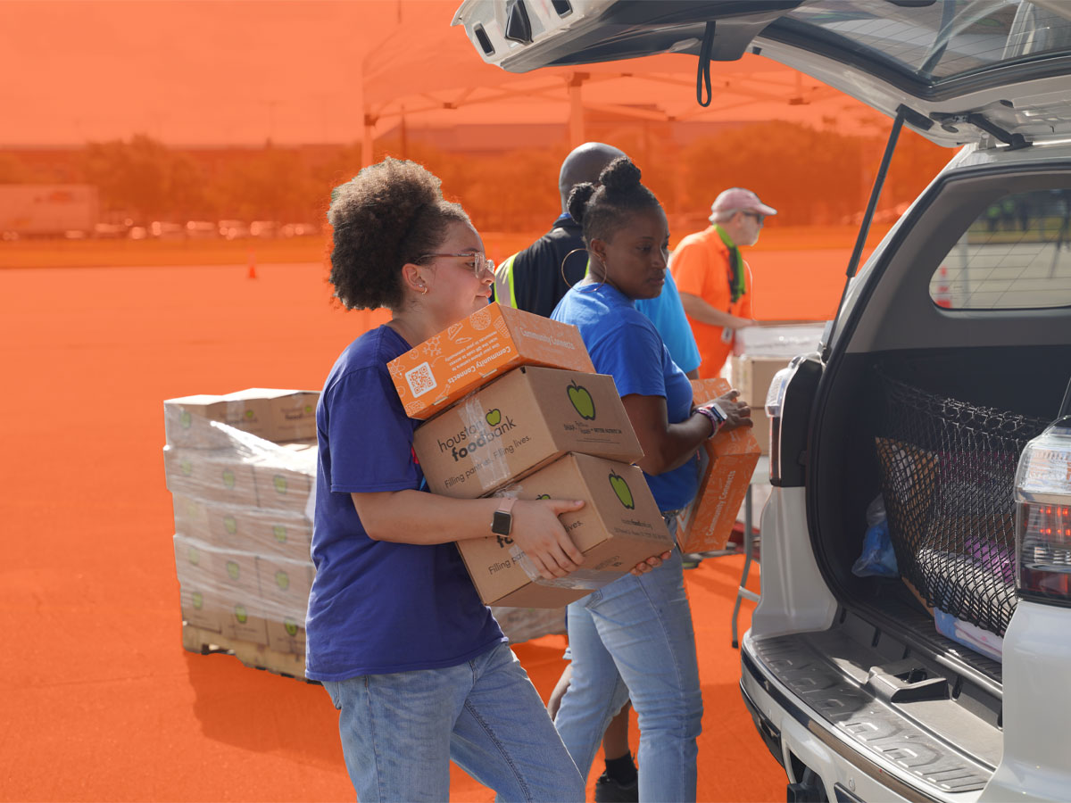 Volunteers pack food into the back of a neighbor's car.