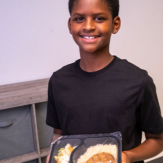 HAMpromo 328×328 Photo of a young boy holding a prepackaged meal.
